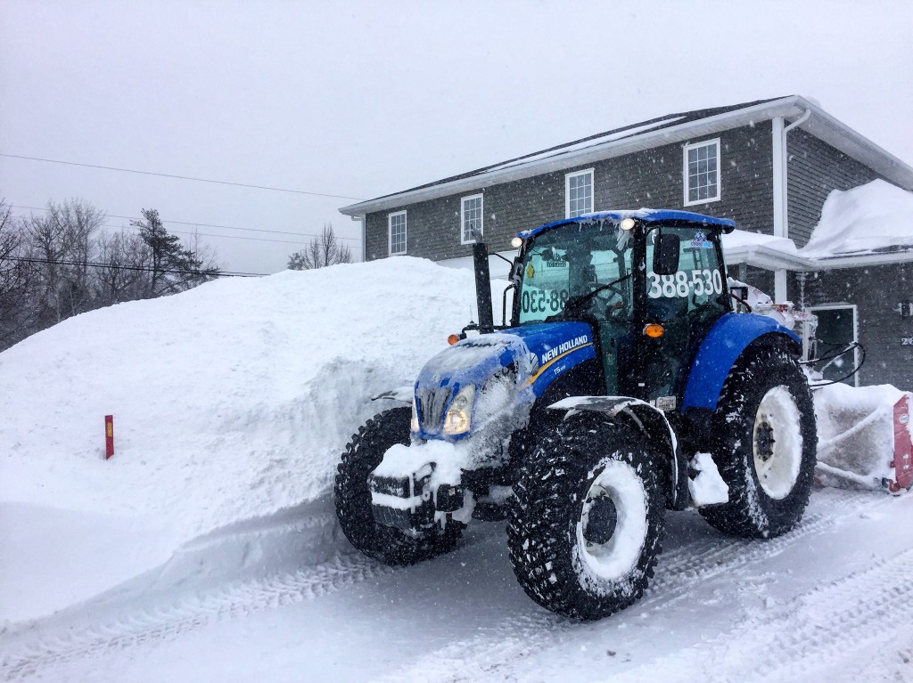 Choreguys New Holland tractor clearing a residential driveway during a snowstorm