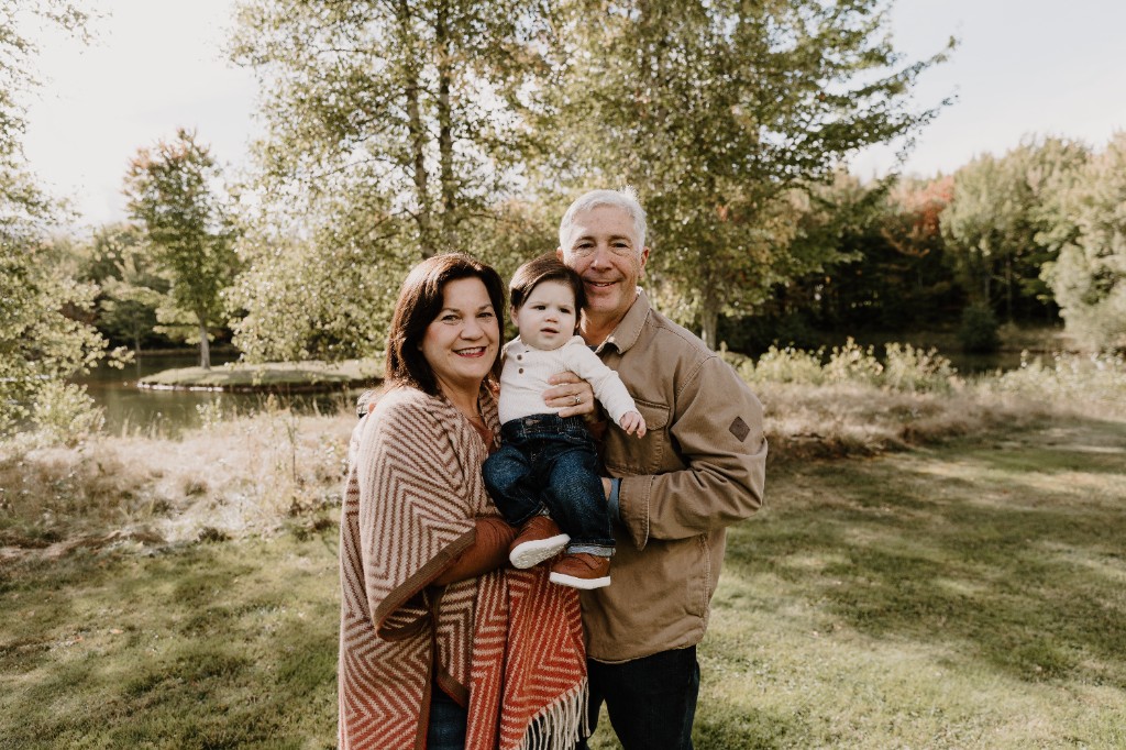 Ross and DeeDee with their young child outdoors beside the water